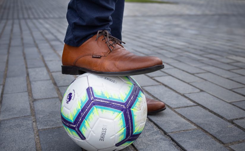 Businessman's shoe on top of a football