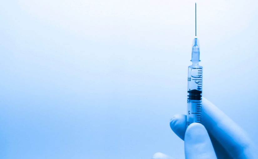 a hand holding a needle containing a vaccine