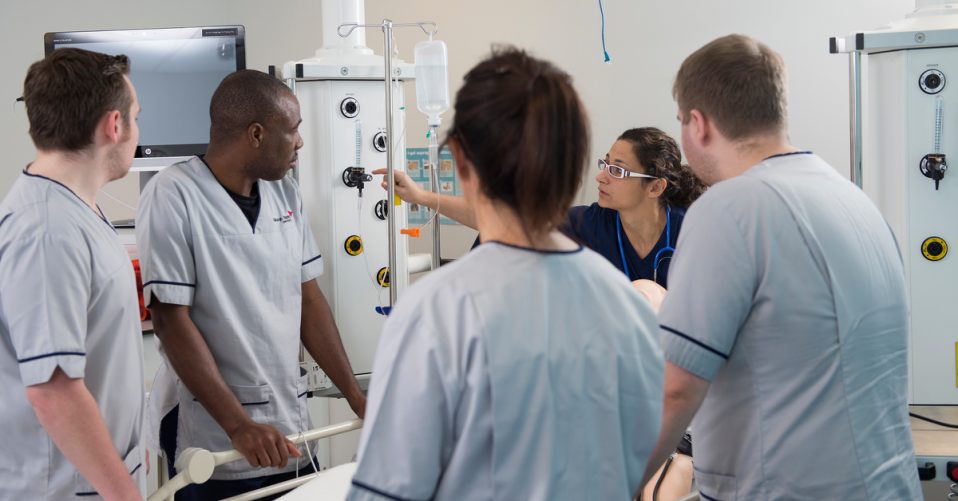 Group of nursing students observing a demonstration of technique.