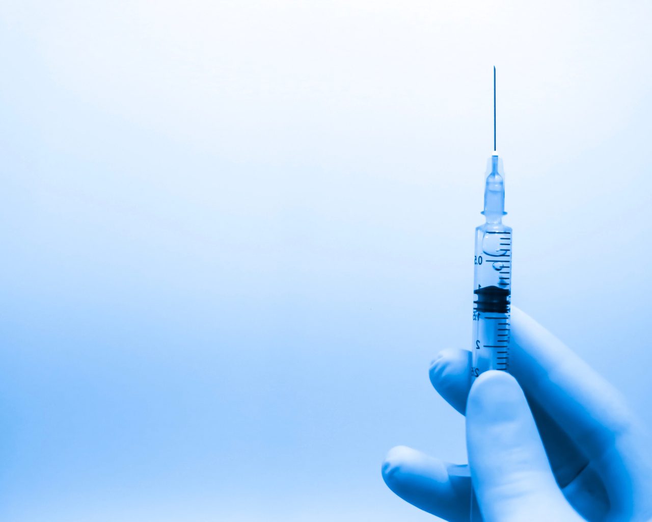 Close-up of a hand wearing a rubber glove holding a needle.