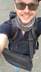 Selfie of smiling researcher carrying laptop bag