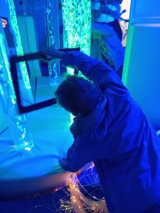 A person holds a black square frame with their hand, with bright lights underneath it.