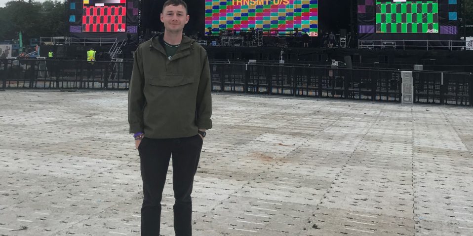 Cameron Hughes standing in front of a stage at a festival's venue